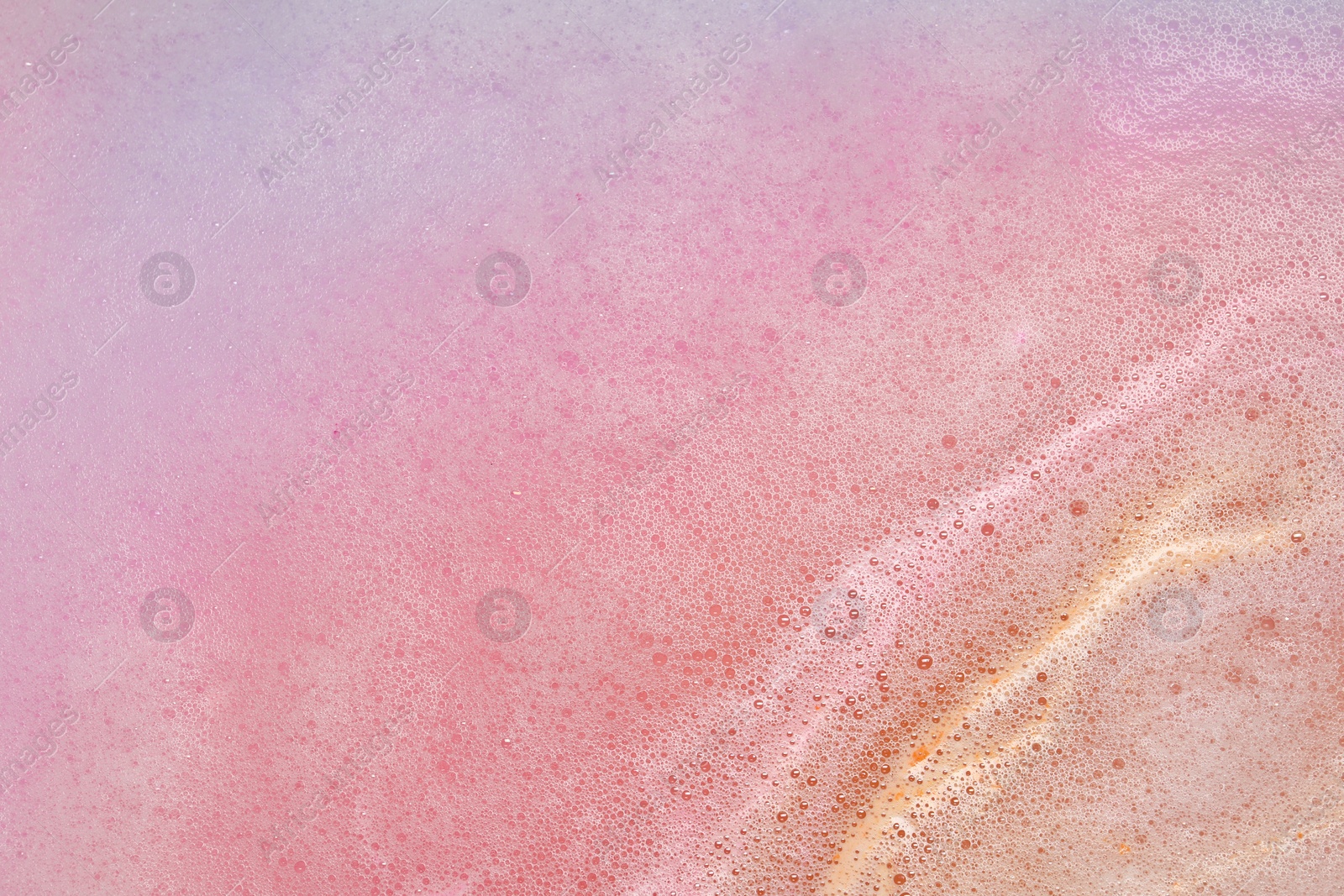 Photo of Colorful foam after dissolving bath bomb in water, closeup