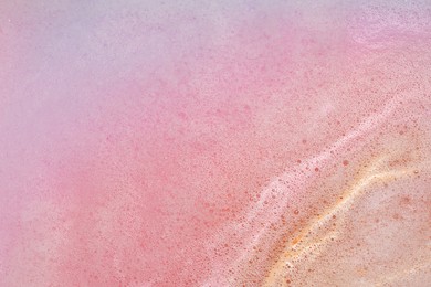 Photo of Colorful foam after dissolving bath bomb in water, closeup