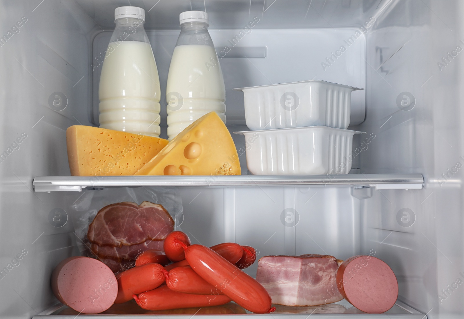 Photo of Different fresh products on shelves in refrigerator