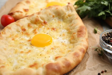 Fresh delicious Adjarian khachapuri on parchment, closeup