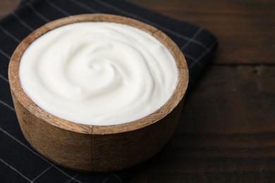 Delicious natural yogurt in bowl on wooden table, closeup