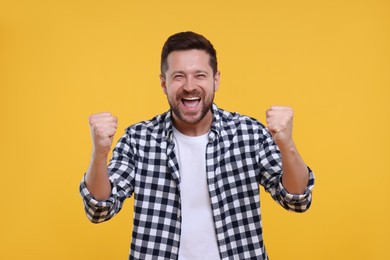 Photo of Emotional sports fan celebrating on yellow background