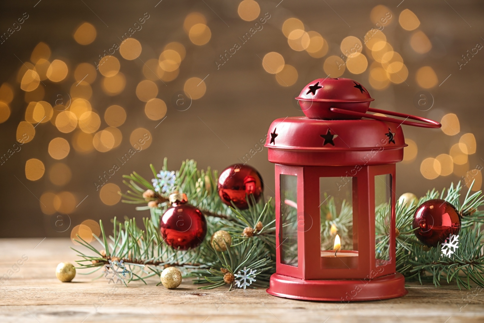 Photo of Composition with lantern and decorated fir branches on table against blurred background. Winter holidays