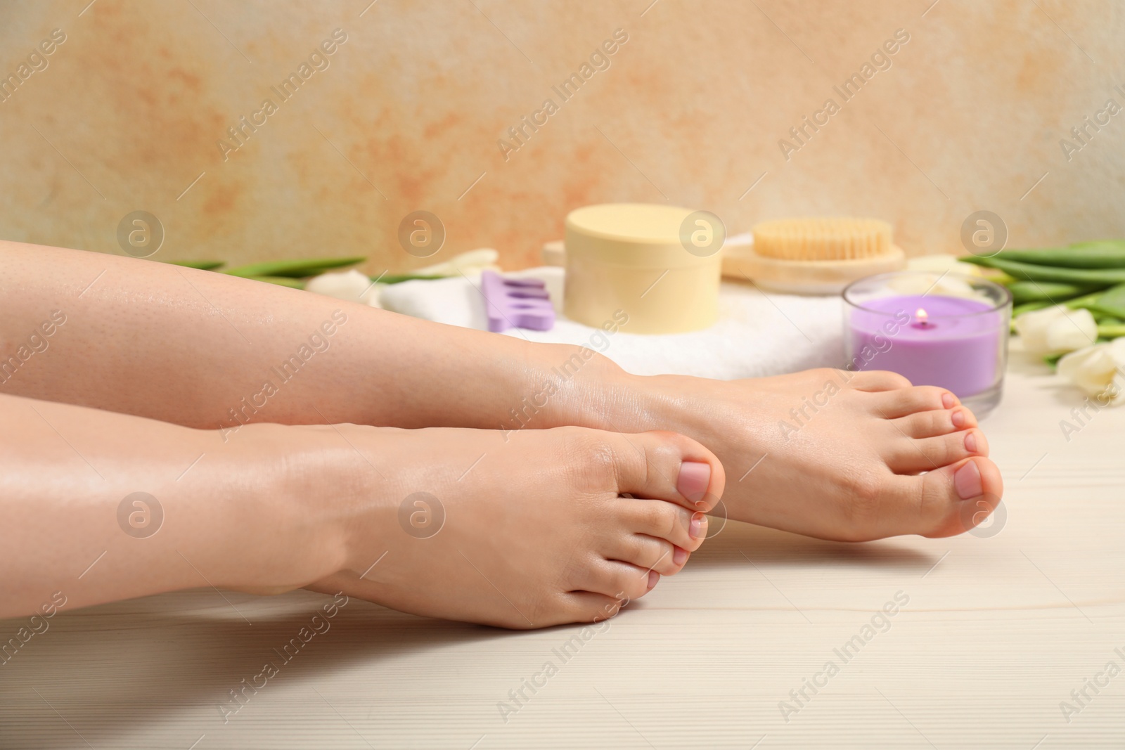 Photo of Woman with neat toenails after pedicure procedure on wooden floor, closeup