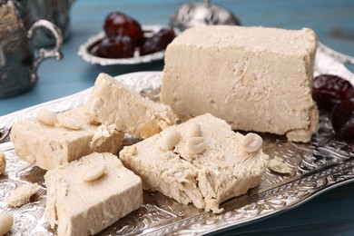 Photo of Pieces of tasty halva and peanuts served on vintage tray, closeup