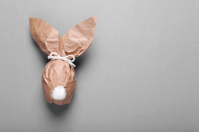 Photo of Easter bunny made of kraft paper and egg on grey background, top view. Space for text