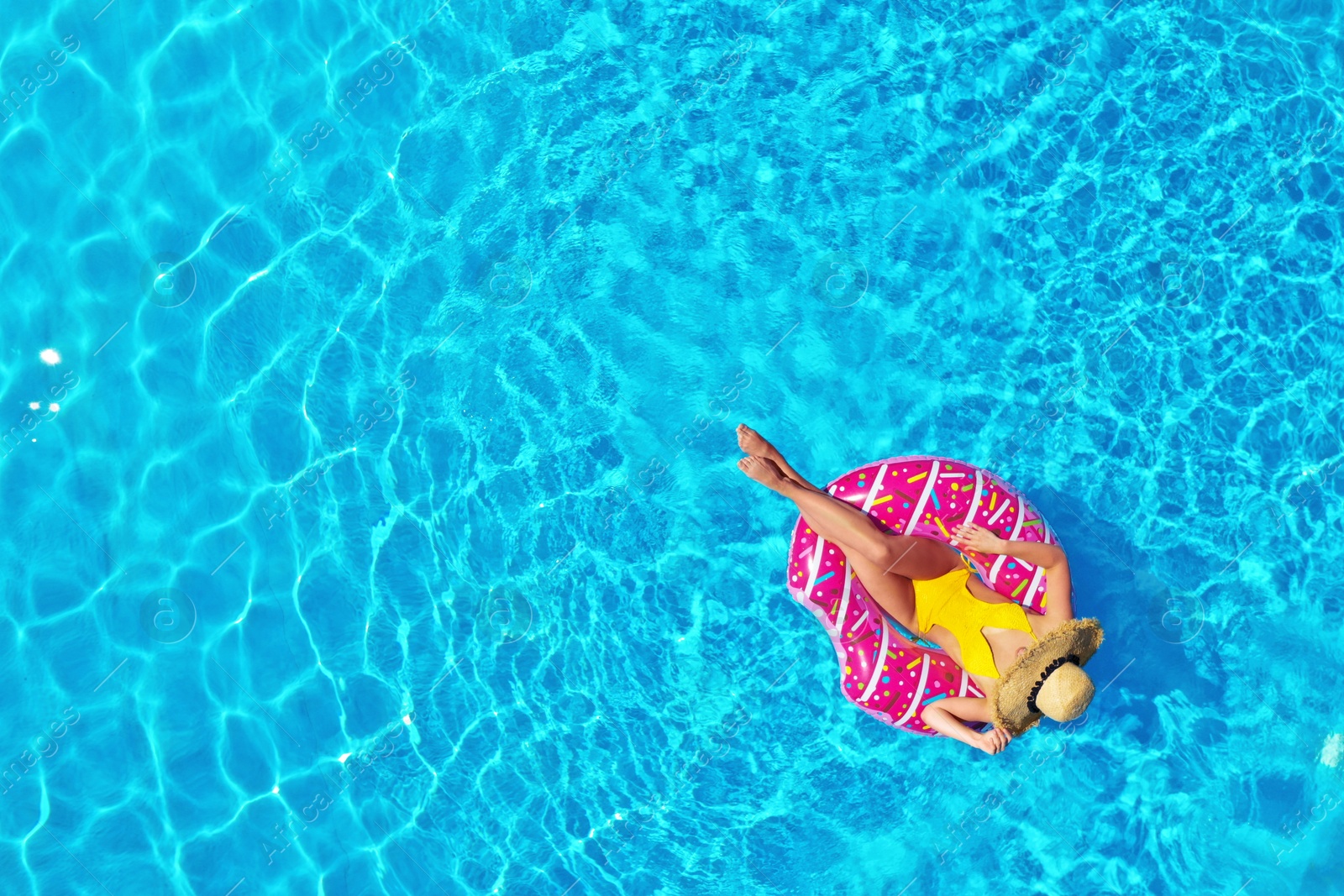 Image of Young woman with inflatable ring in swimming pool, top view. Space for text