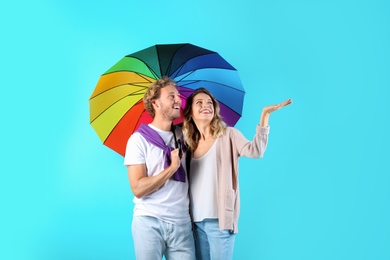 Couple with rainbow umbrella on color background