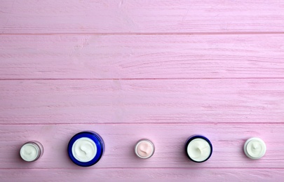 Photo of Jars with body cream on wooden background