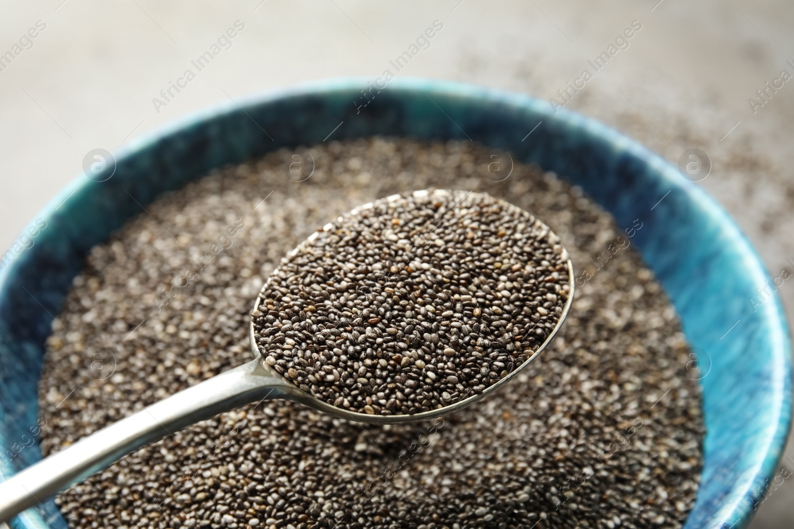 Photo of Spoon with chia seeds over bowl, closeup