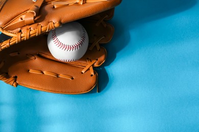 Baseball glove and ball on light blue background. Space for text