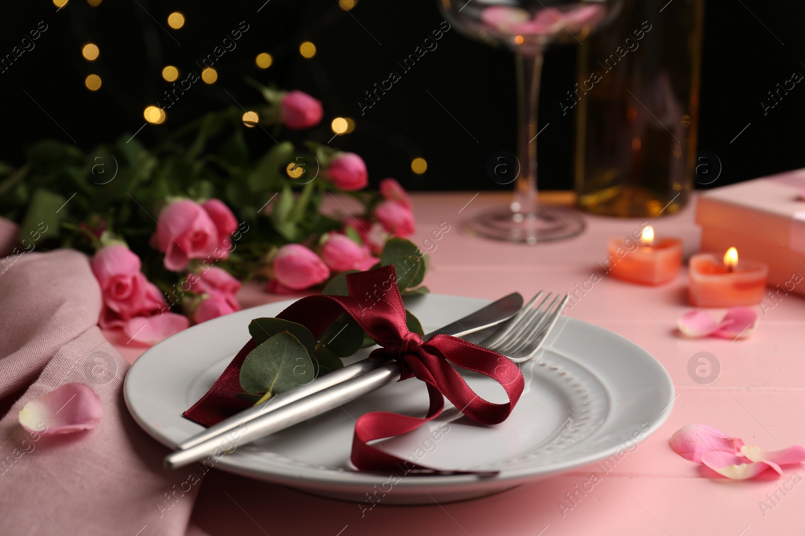 Photo of Place setting with roses and candles on pink wooden table, closeup. Romantic dinner