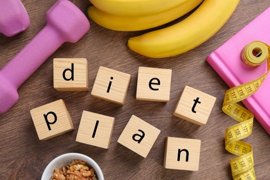 Phrase Diet Plan made of cubes, fitness items and products on wooden table, flat lay. Weight loss concept