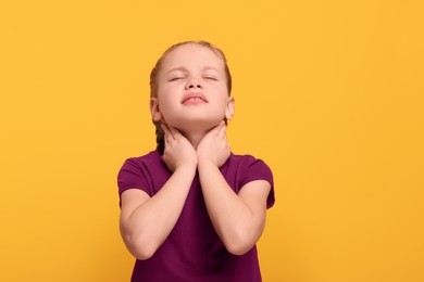 Girl suffering from sore throat on orange background