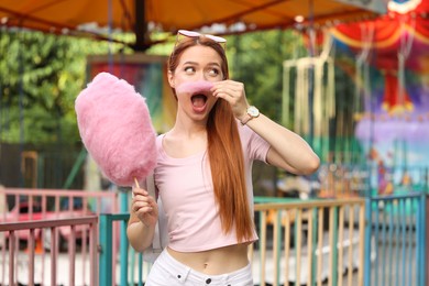 Photo of Beautiful woman having fun with cotton candy at funfair