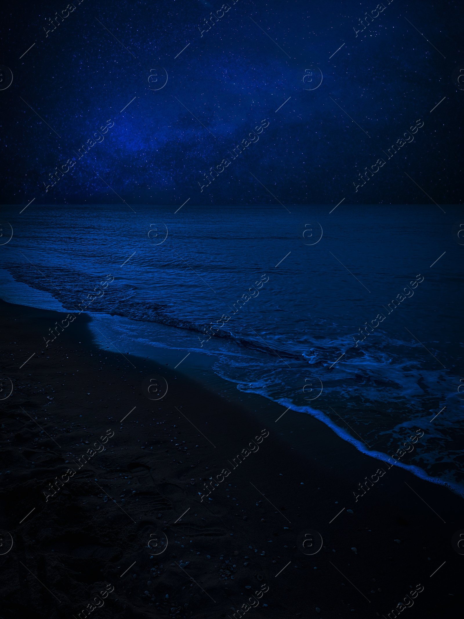 Image of Sea waves rolling onto sandy beach under starry sky at night