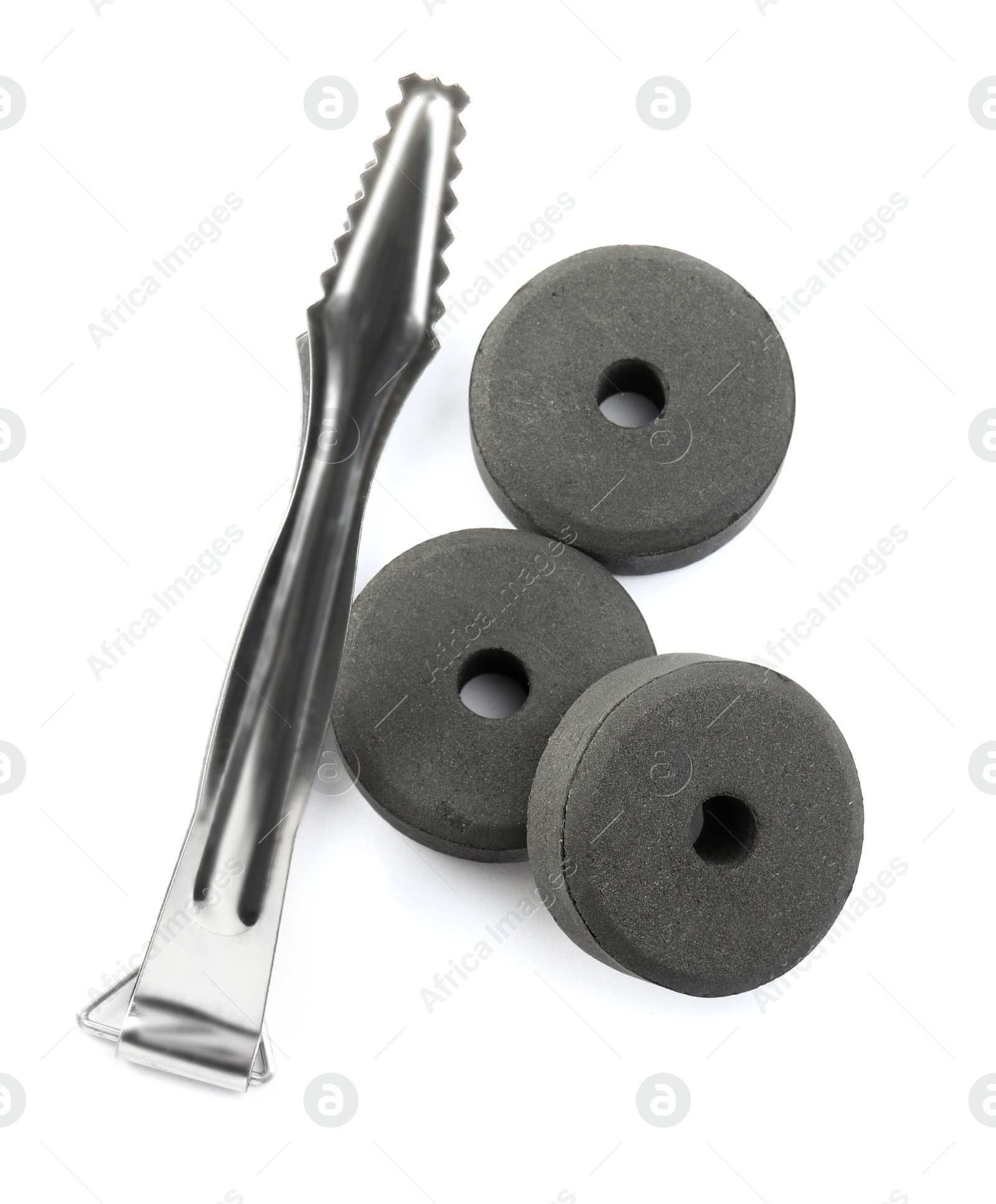 Photo of Charcoal rings for hookah and tongs on white background, top view