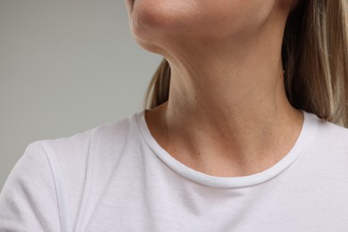 Mature woman with healthy skin on grey background, closeup