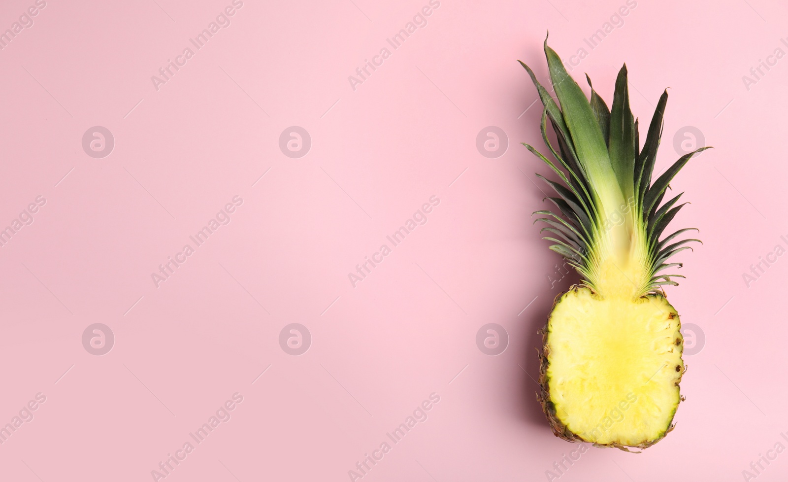 Photo of Half of pineapple on pink background, top view. Space for text