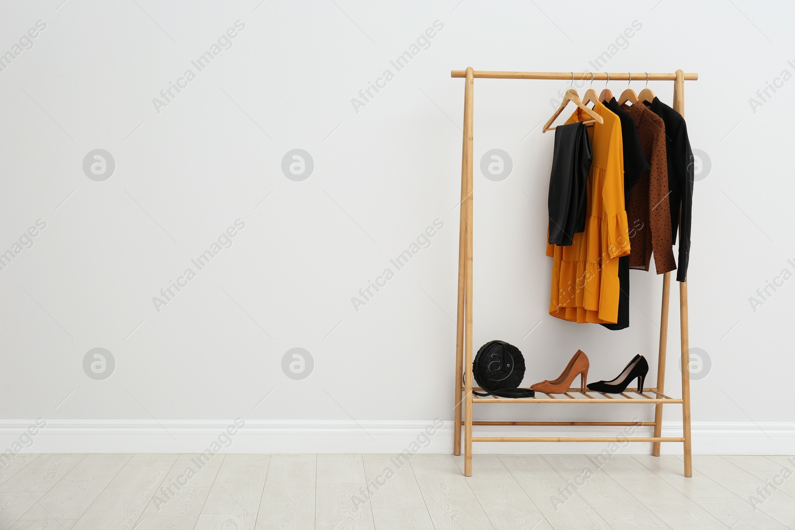 Photo of Wooden rack with stylish clothes in room. Space for text