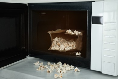 Open microwave oven with fresh popcorn on table