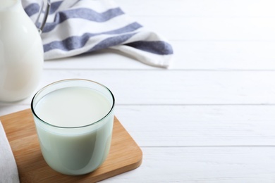 Photo of Glass of fresh milk on white wooden table. Space for text