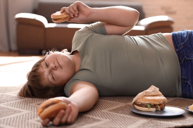 Overweight boy with fast food at home