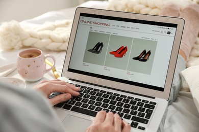 Photo of Woman using laptop for online shopping indoors, closeup