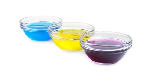 Glass bowls with different food coloring on white background