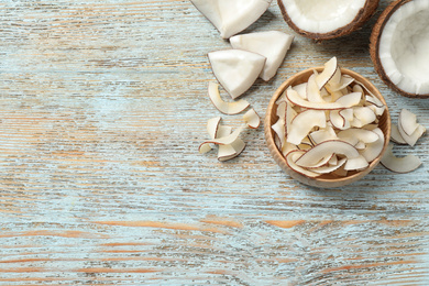 Photo of Flat lay composition with tasty coconut chips on light blue wooden table. Space for text