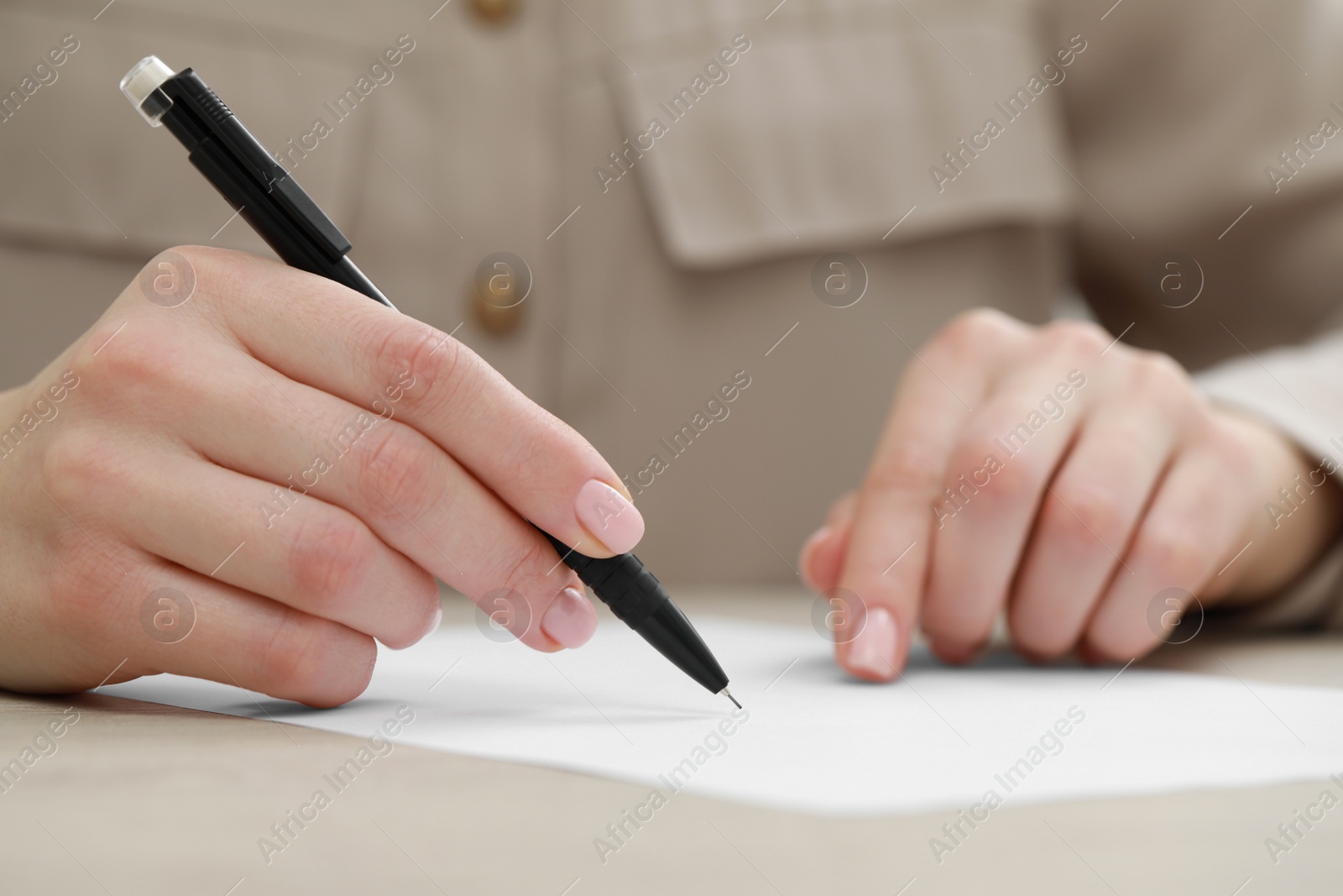 Photo of Woman writing on sheet of paper at light table, closeup