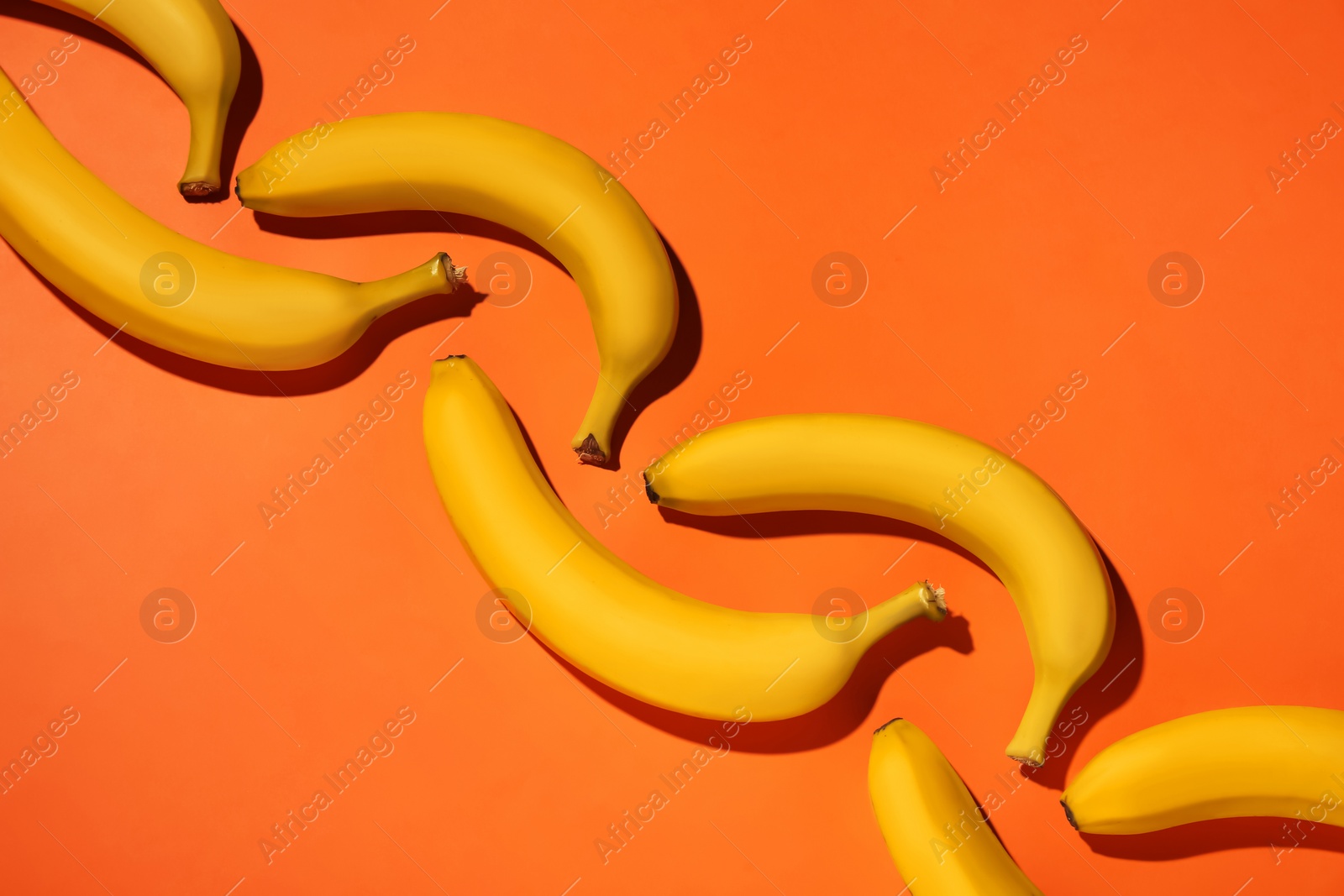 Photo of Ripe yellow bananas on coral background, flat lay