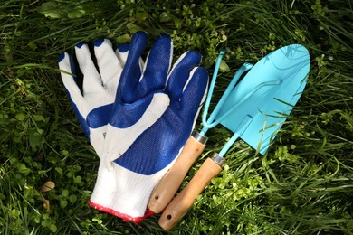 Photo of Gardening gloves and tools on grass outdoors, flat lay