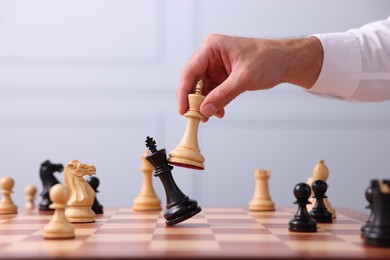 Photo of Man moving king chess piece at checkerboard indoors, closeup