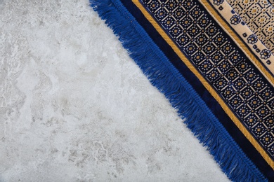 Muslim prayer rug and space for text on grey background, top view