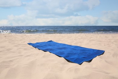 Photo of Soft blue beach towel on sandy seashore