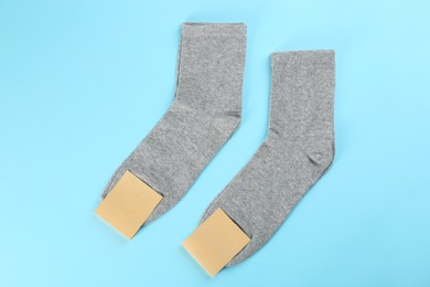 Photo of Grey cotton socks on light blue background, flat lay