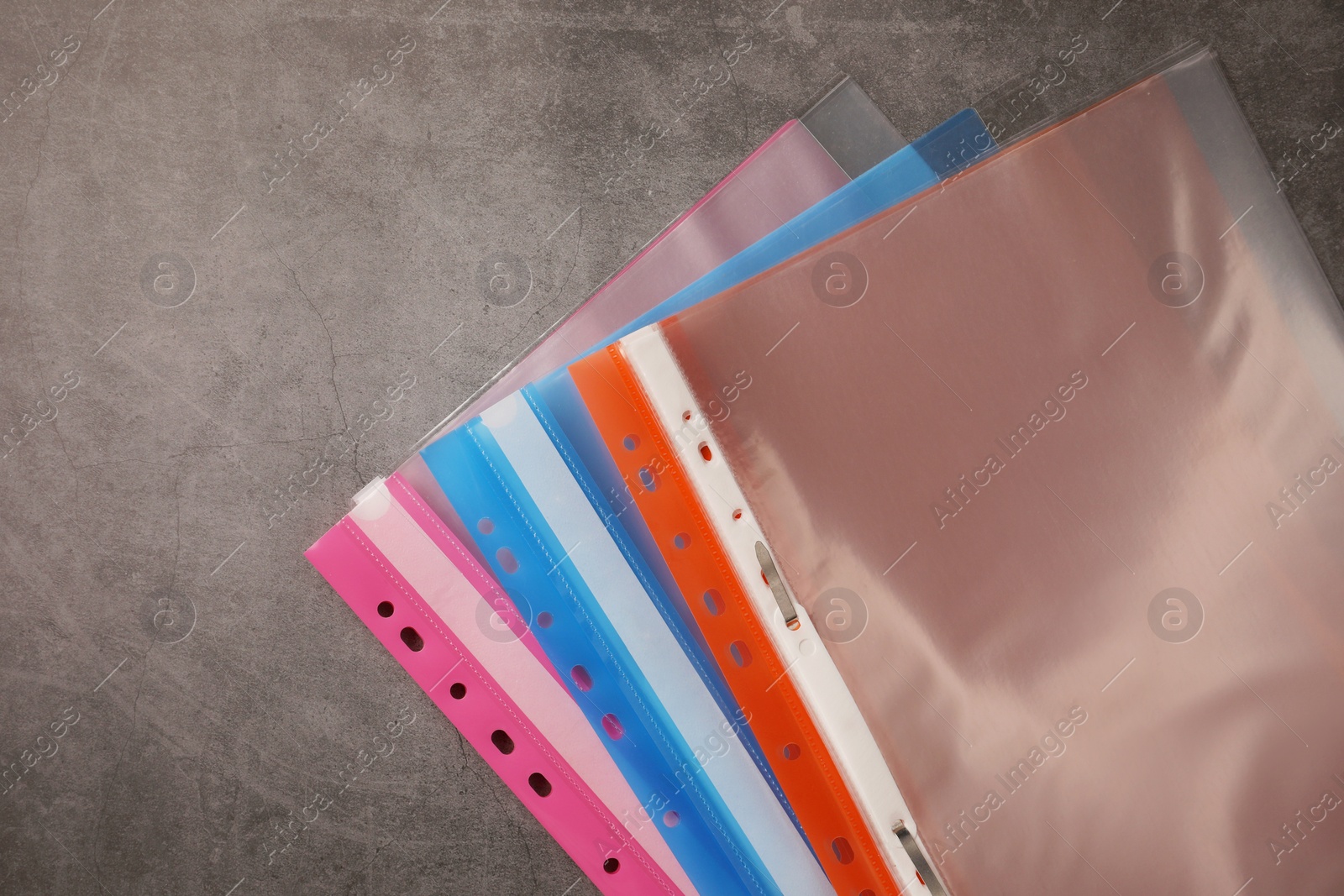 Photo of File folders with punched pockets on grey table, flat lay. Space for text