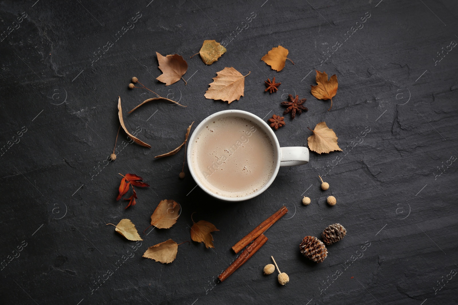 Photo of Flat lay composition with cup of hot drink and autumn leaves on black table. Cozy atmosphere
