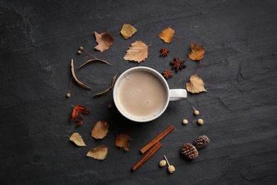 Flat lay composition with cup of hot drink and autumn leaves on black table. Cozy atmosphere