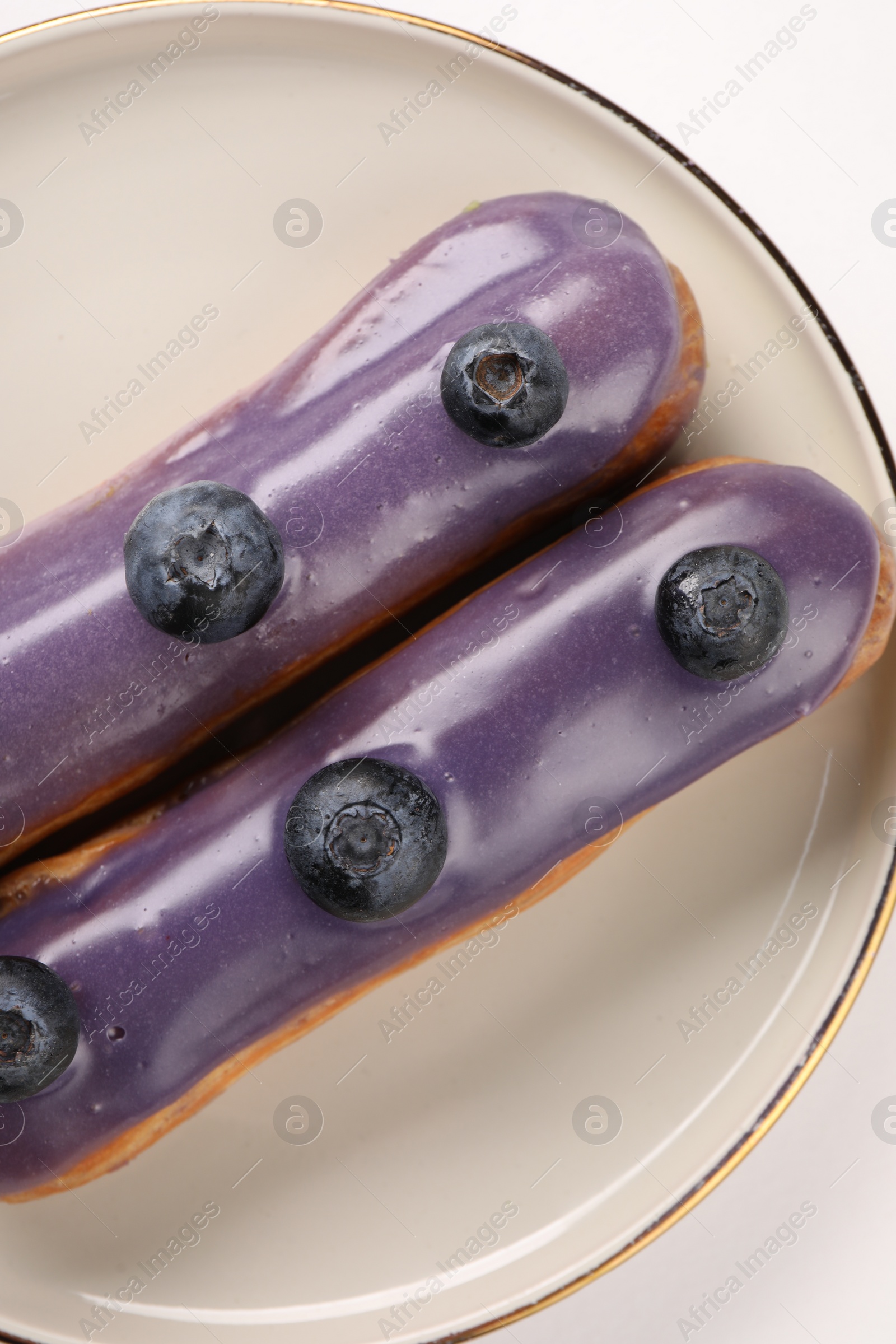 Photo of Delicious eclairs decorated with blueberries on white background, top view