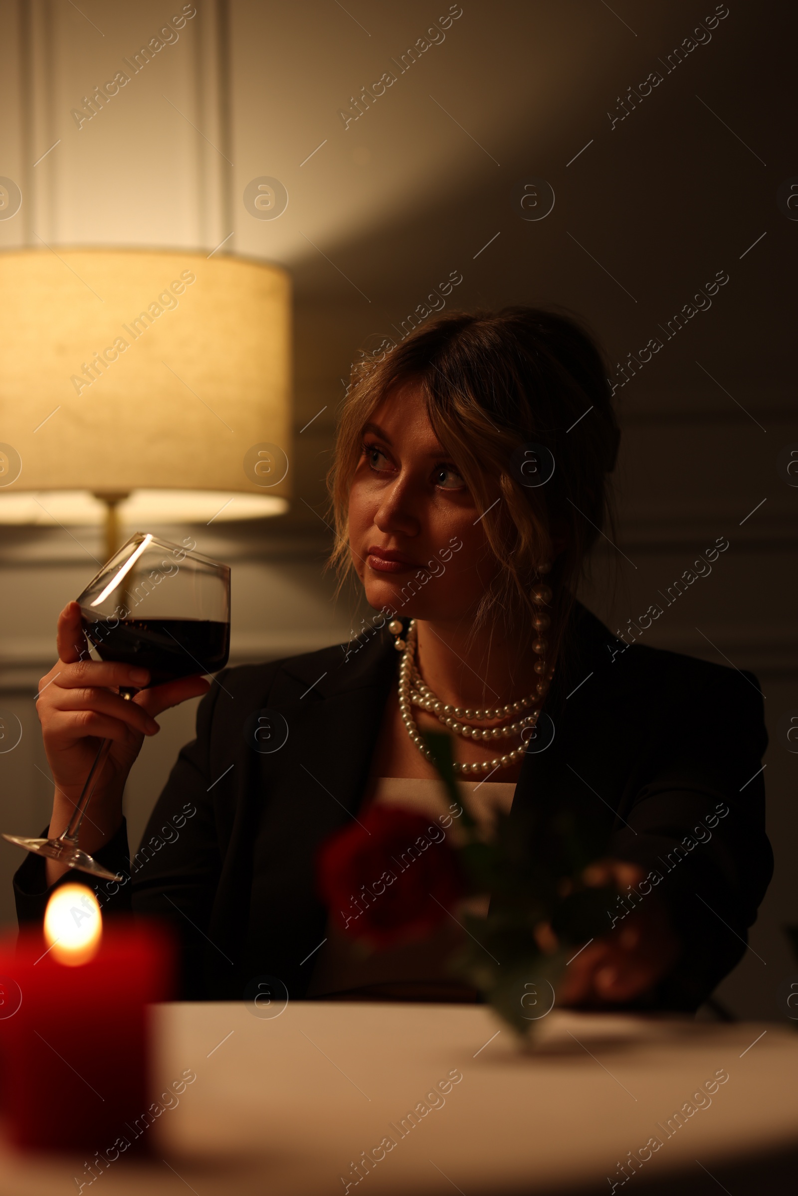 Photo of Beautiful young woman with glass of wine at table in restaurant