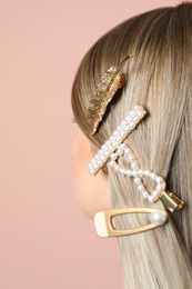 Young woman with beautiful different hair clips on pink background, closeup