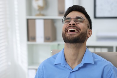 Photo of Portrait of handsome young man laughing in office, space for text