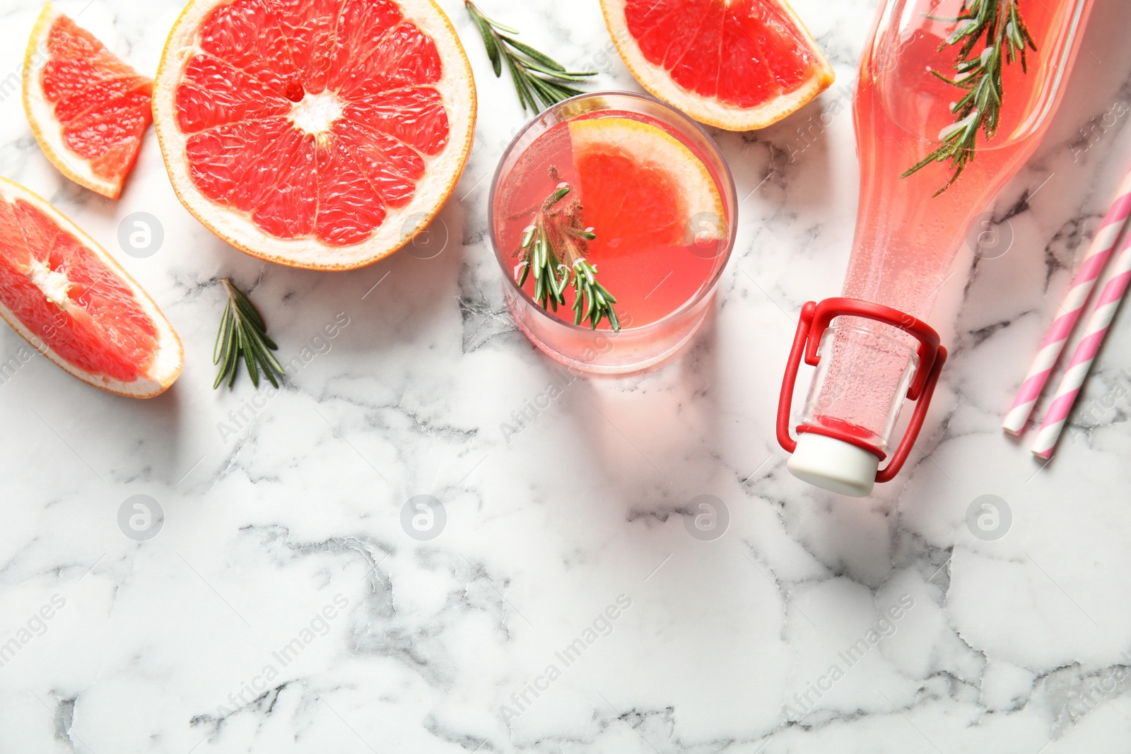 Photo of Flat lay composition with grapefruits, glass of cocktail and bottle on marble background. Space for text