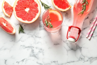 Flat lay composition with grapefruits, glass of cocktail and bottle on marble background. Space for text