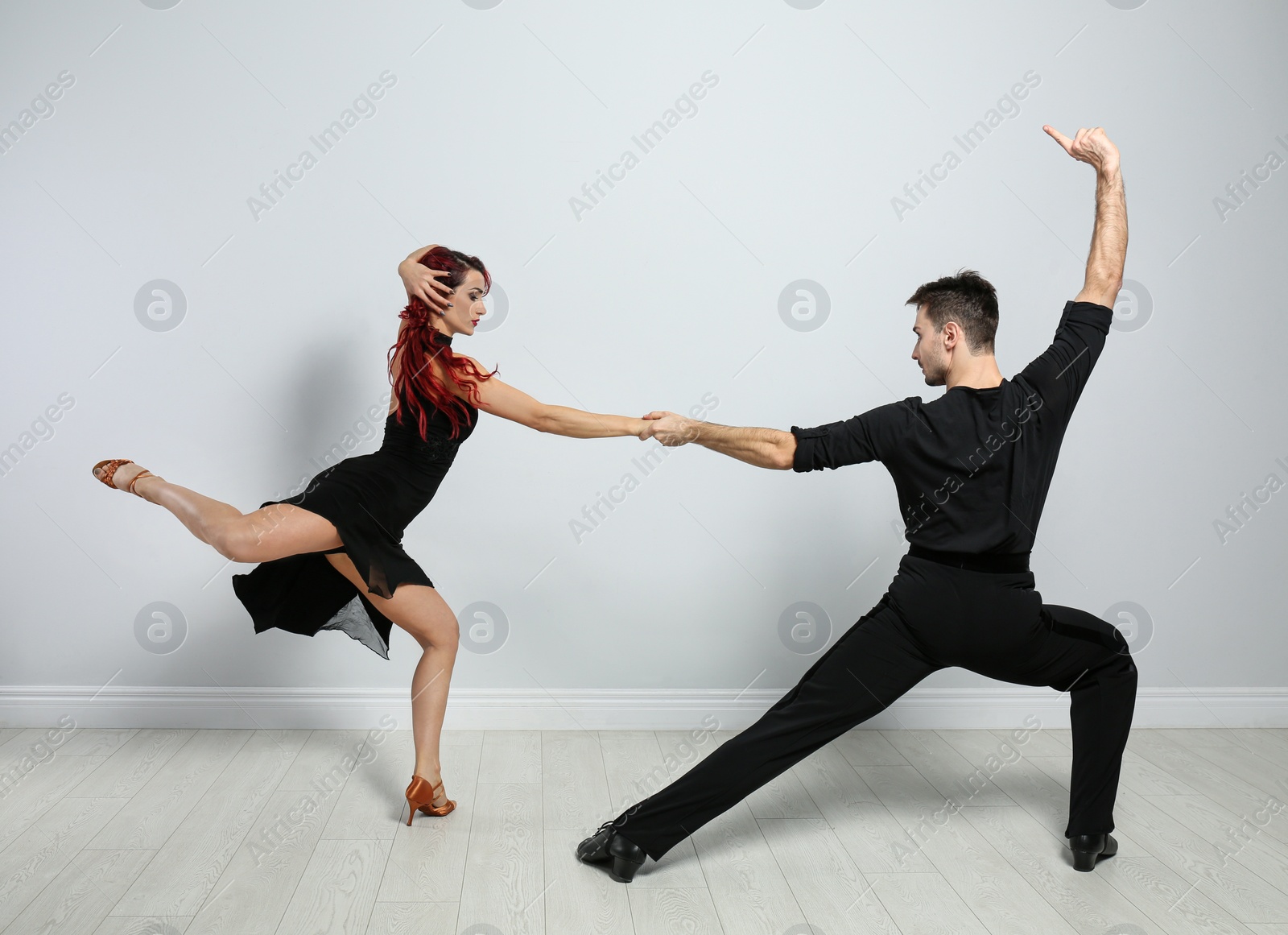 Photo of Beautiful young couple dancing near light wall