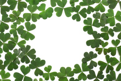 Photo of Frame of green clover leaves on white background, flat lay