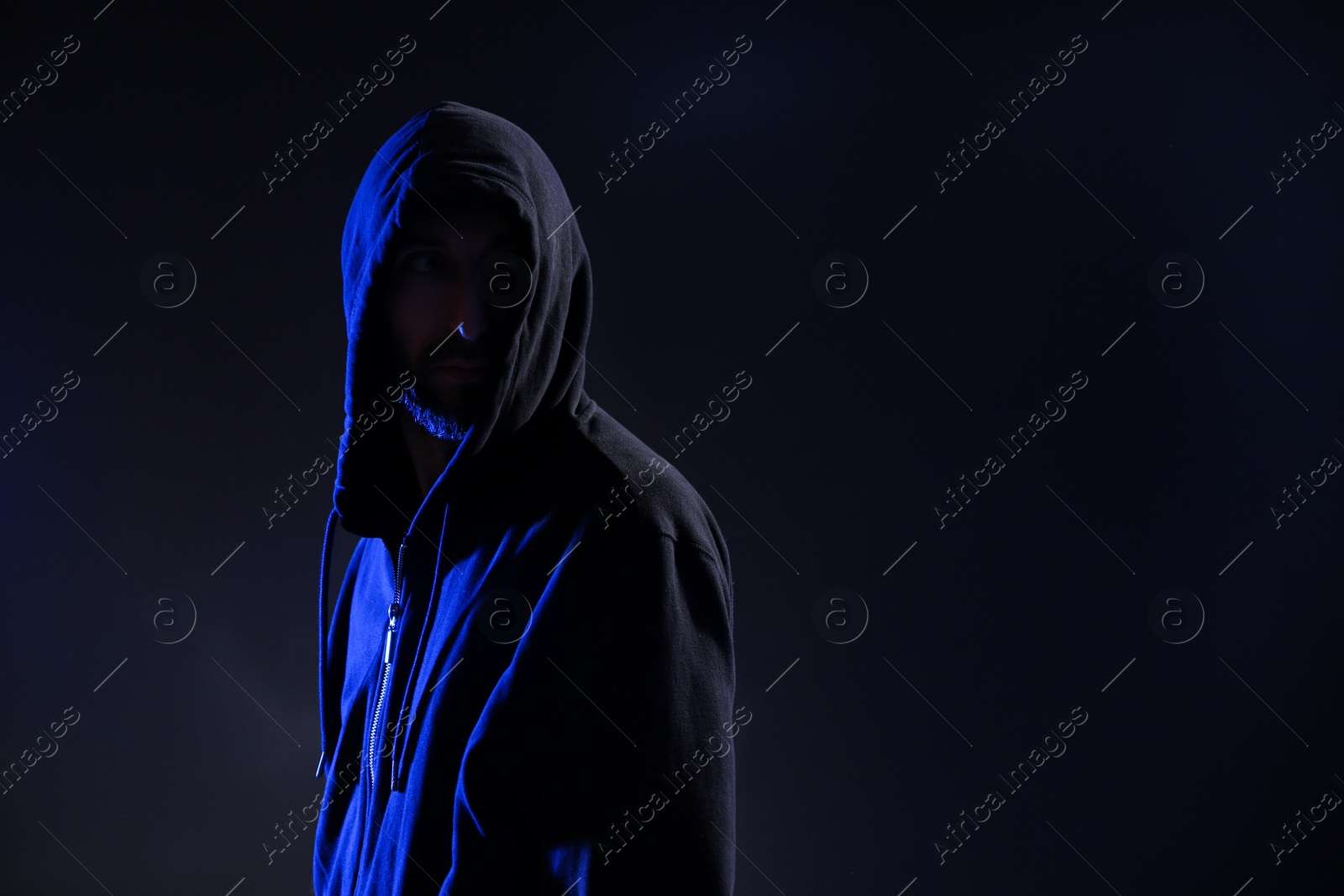 Photo of Man in hood on dark background, space for text. Cyber crime