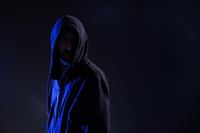 Photo of Man in hood on dark background, space for text. Cyber crime